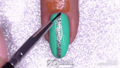 A Brush Is Being Used To Paint A Green Nail With A Silver Line GIF