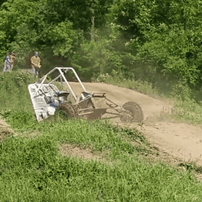 A Buggy Is Driving Down A Dirt Road With People Watching In The Background GIF