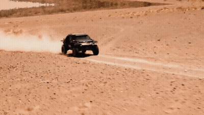 A Buggy Is Flying Through The Air In A Desert Landscape GIF