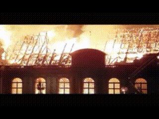 A Building Is On Fire With A Lot Of Flames Coming Out Of The Roof GIF