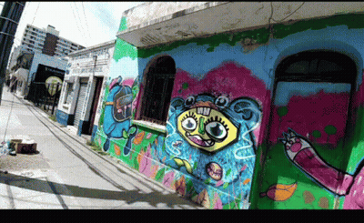 A Building With Graffiti On The Side Of It Including A Cartoon Face GIF