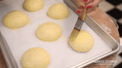 A Bunch Of Buns Are Sitting On A Tray With A Bigger Bolder Baking Logo On The Bottom GIF