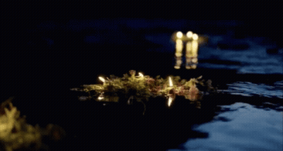 A Bunch Of Candles Floating In The Water At Night GIF