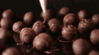 A Bunch Of Chocolate Balls Are Being Covered With Chocolate GIF