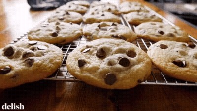 A Bunch Of Chocolate Chip Cookies On A Cooling Rack With The Word Delish Below Them GIF