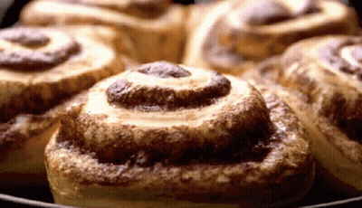 A Bunch Of Cinnamon Rolls Are Sitting On A Pan GIF