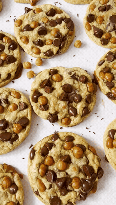 A Bunch Of Cookies With Chocolate Chips And Caramel Bits On Them GIF