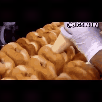 A Bunch Of Donuts Are Being Made In A Donut Shop . GIF