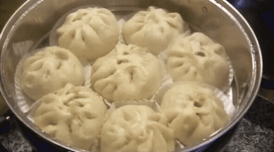 A Bunch Of Dumplings Are Cooking In A Steamer . GIF