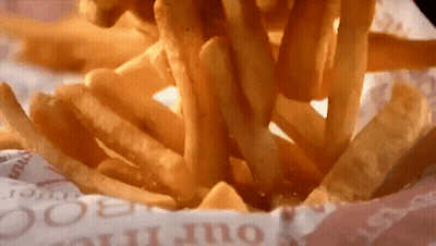 A Bunch Of French Fries Are Being Poured Out Of A Container GIF