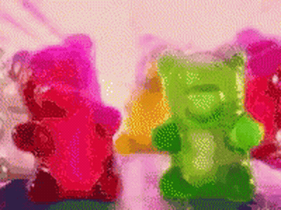 A Bunch Of Gummy Bears In Different Colors Are Sitting On A Table GIF