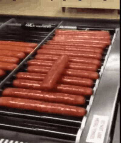 A Bunch Of Hot Dogs On A Conveyor Belt With A Sign That Says " Do Not Touch " GIF