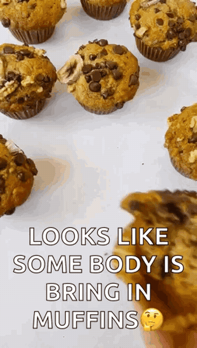 A Bunch Of Muffins Are Sitting On A Table And A Person Is Holding A Piece Of Chocolate Cake . GIF
