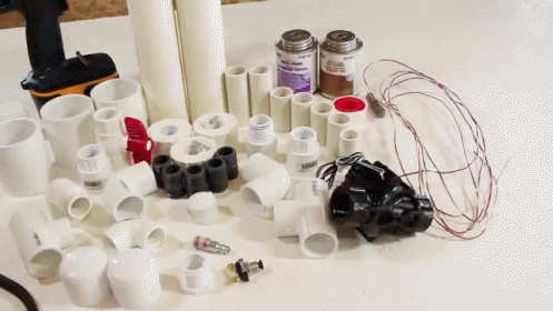A Bunch Of Plastic Pipes And Tools On A Table With A Bottle Of Acetone GIF