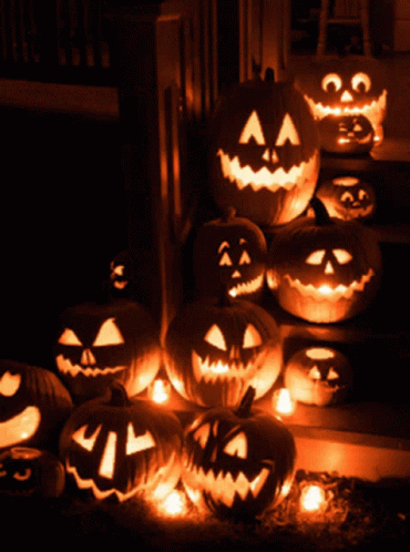 A Bunch Of Pumpkins With Faces Carved Into Them Are Lit Up In The Dark GIF