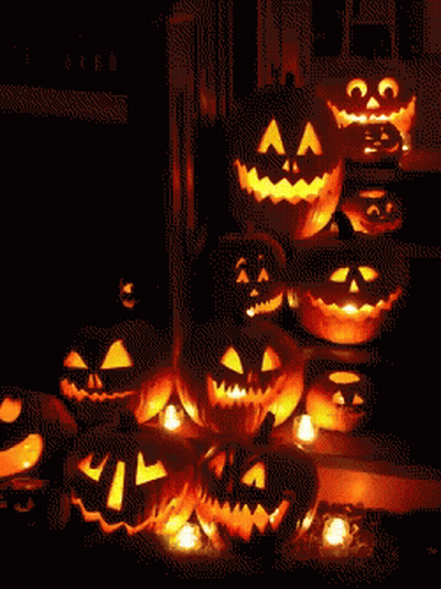 A Bunch Of Pumpkins With Faces Carved Into Them Are Lit Up In The Dark GIF
