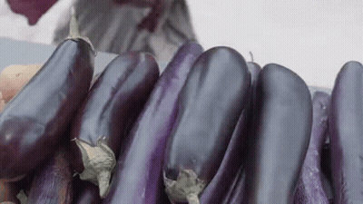 A Bunch Of Purple Eggplants Are Sitting On Top Of A Table . GIF