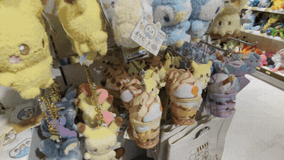 A Bunch Of Stuffed Animals Are Hanging On A Shelf With A Tag That Says ' Pokemon ' On It GIF
