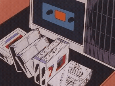 A Bunch Of Tapes Are Sitting On A Table Next To A Cassette Tape Player . GIF