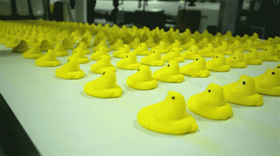 A Bunch Of Yellow Rubber Ducks Are Lined Up On A Conveyor Belt GIF