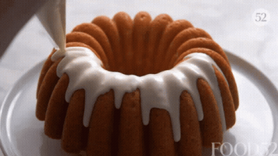 A Bundt Cake With White Frosting Is On A Plate With Food52 Written On It GIF