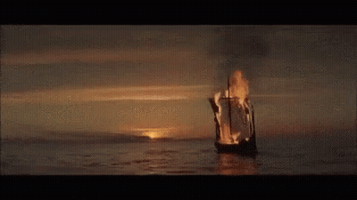 A Burning Boat Is Floating On Top Of A Body Of Water . GIF