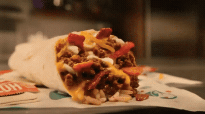 A Burrito With A Lot Of Toppings Is On A Table GIF