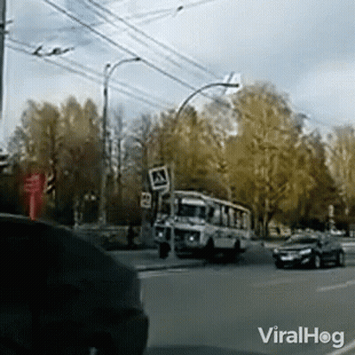 A Bus Is Driving Down A Street Next To A Sign That Says A GIF
