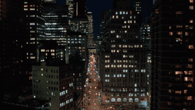 A Busy City Street At Night With A Lot Of Buildings GIF