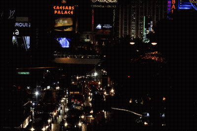 A Busy City Street At Night With A Sign For The Caesars Palace In The Background GIF