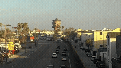 A Busy City Street With A Yellow Sign That Says Motel Inn GIF