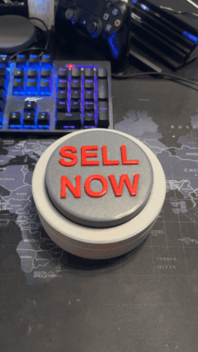 A Button That Says Sell Now Is On A Desk GIF