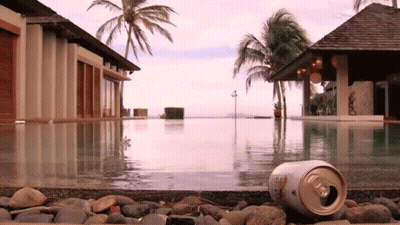 A Can Of Beer Is Laying On The Edge Of A Pool GIF