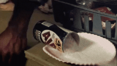 A Can Of Lays Chips Is Being Poured Into A Paper Plate On A Table GIF