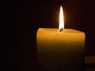 A Candle Is Lit Up In The Dark And Has A Blue Candle Sticking Out Of It GIF
