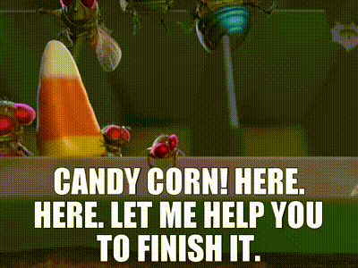 A Candy Corn Cone Is Sitting On A Table Next To A Bag Of Candy . GIF