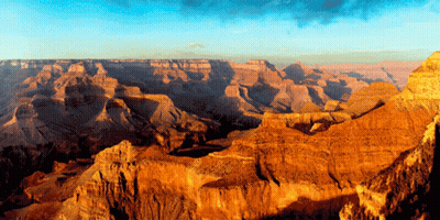 A Canyon With A Blue Sky And A Few Clouds GIF