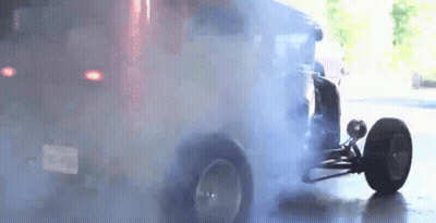 A Car Is Doing A Burnout In A Garage With Smoke Coming Out Of The Tires . GIF