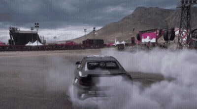 A Car Is Drifting On A Race Track With Smoke Coming Out Of It GIF