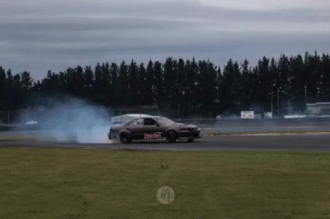A Car Is Drifting On A Track With Smoke Coming Out Of The Tires .. GIF