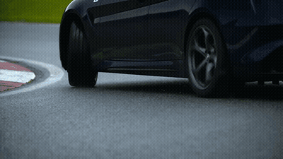 A Car Is Driving Around A Curve On A Race Track GIF