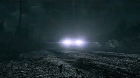 A Car Is Driving Down A Foggy Road At Night In The Woods . GIF
