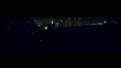 A Car Is Driving Down A Highway At Night With A Reflection Of A Building In The Background GIF