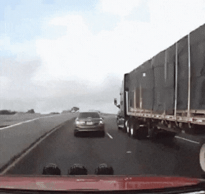 A Car Is Driving Down A Highway Next To A Truck GIF
