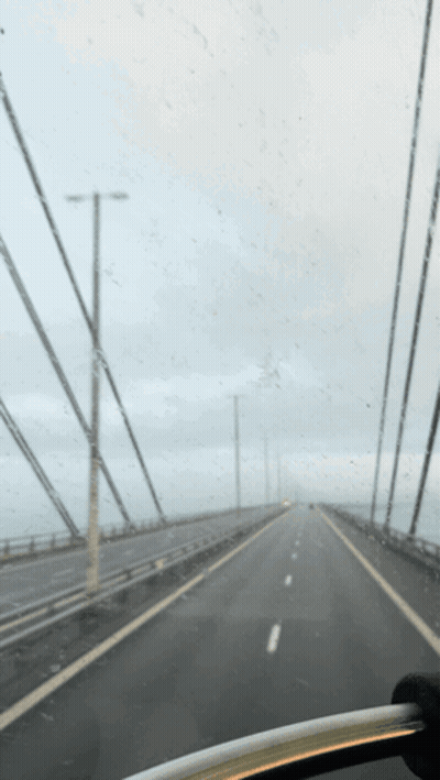 A Car Is Driving Down A Highway With A Gray Sky In The Background GIF
