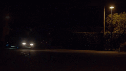 A Car Is Driving Down A Road At Night GIF