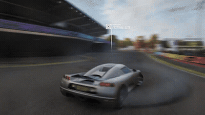 A Car Is Driving Down A Road In Front Of A Festival Site GIF