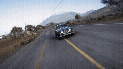 A Car Is Driving Down A Road With A Mountain In The Background GIF