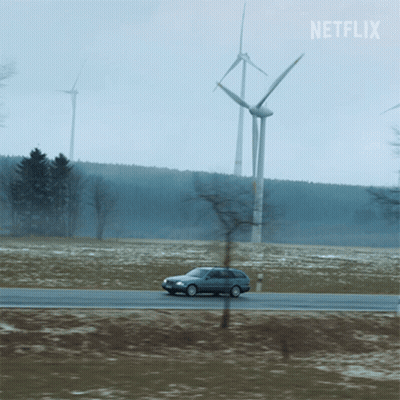 A Car Is Driving Down A Road With Windmills In The Background And A Netflix Logo GIF