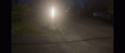 A Car Is Driving Down A Street At Night With A Bright Light Shining Through The Fog GIF
